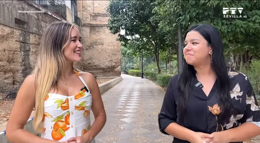 Alba, Schöpferin der Casa Sefardí und Guide bei Altai Turismo, mit der Moderatorin von „Paseando x Sevilla“ auf einem Gartenweg in Sevilla an einer alten Mauer