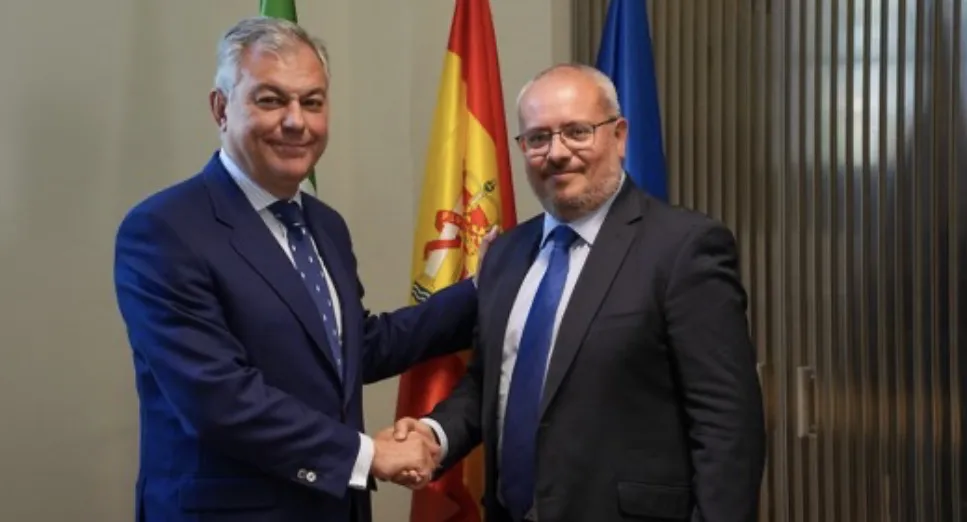 José Luis Sanz und César Fernández geben sich die Hand vor den Flaggen Andalusiens, Spaniens und der Europäischen Union