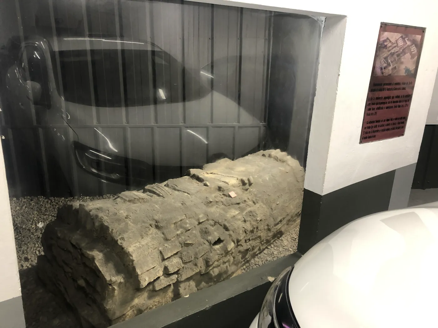 Ziegelgrab des mittelalterlichen jüdischen Friedhofs hinter Glas in der Tiefgarage Cano y Cueto, umgeben von parkenden Autos