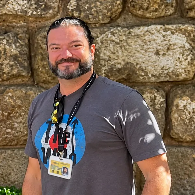 Samuel, guide at Altai Turismo, in front of a stone wall, wearing his guide badge