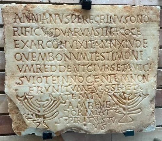 Römischer Grabstein mit lateinischer Inschrift und zwei erhaben gearbeiteten Menorot: Epitaph des Annianus Peregrinus, Exarchon zweier Synagogen