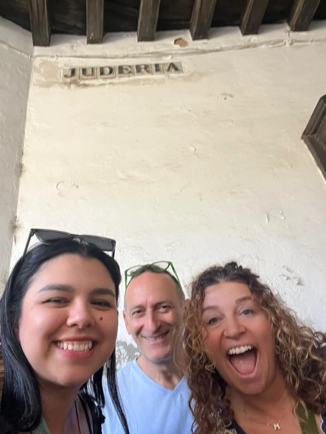 Drei Besucher lächeln unter dem „Judería“-Schild, dem Torweg ins alte Judenviertel